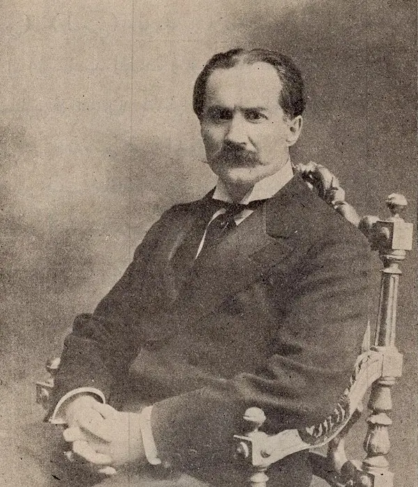 Rıza Tevfik Bölükbaşı'nın bıyıklı, takım elbiseli hâliyle oymalı bir koltukta oturduğu 1910 tarihli fotoğraf