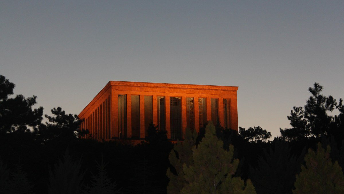 10 Kasım'da Atatürk'ü anarken gün batımında turuncu ışıkla aydınlanan Anıtkabir ve önündeki çam ağaçlarının silueti