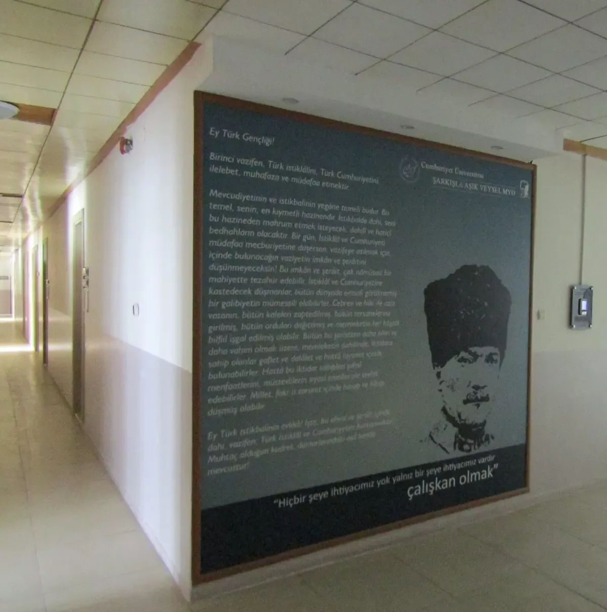 Bir okul koridorunun duvarını kaplayan, Gençliğe Hitabe metni ve kalpaklı Atatürk portresinin bulunduğu koyu renkli büyük pano