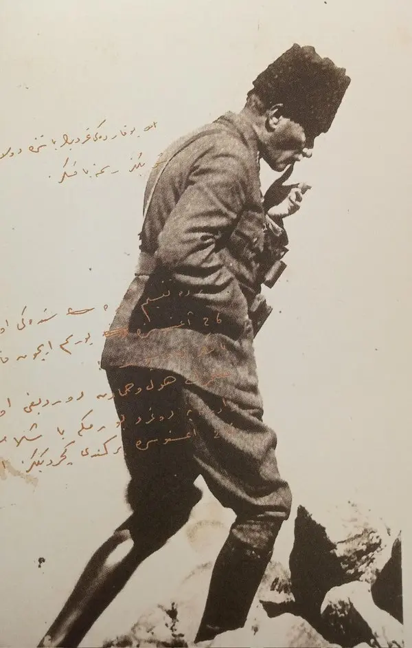 Kalpaklı ve üniformalı Mustafa Kemal Paşa'nın kayalık bir tepede yürürken eliyle yüzünü siper ettiği siyah-beyaz fotoğraf