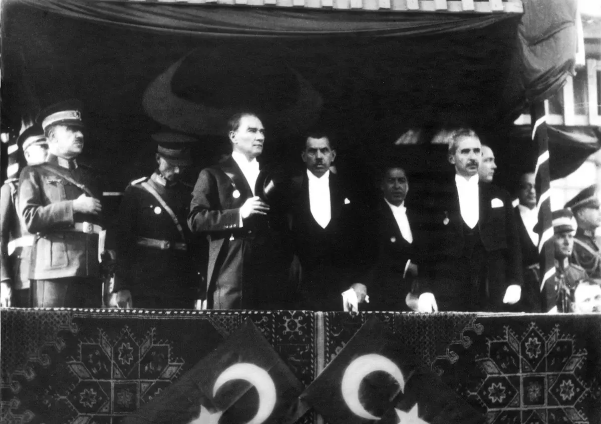 1933'te Cumhuriyet'in onuncu yıl kutlamalarında, önü kilim ve ay yıldızlı bayraklarla süslü tribünde duran Mustafa Kemal Atatürk ve devlet erkânı