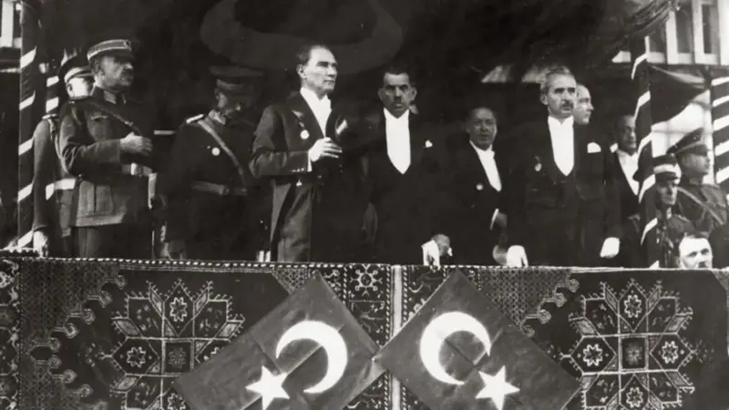 Atatürk, Fevzi Çakmak, Kâzım Özalp ve İsmet İnönü, Cumhuriyet’in 10. yıl dönümü kutlamalarında halılarla ve iki Türk bayrağıyla süslenmiş tribünde, Ankara, 29 Ekim 1933