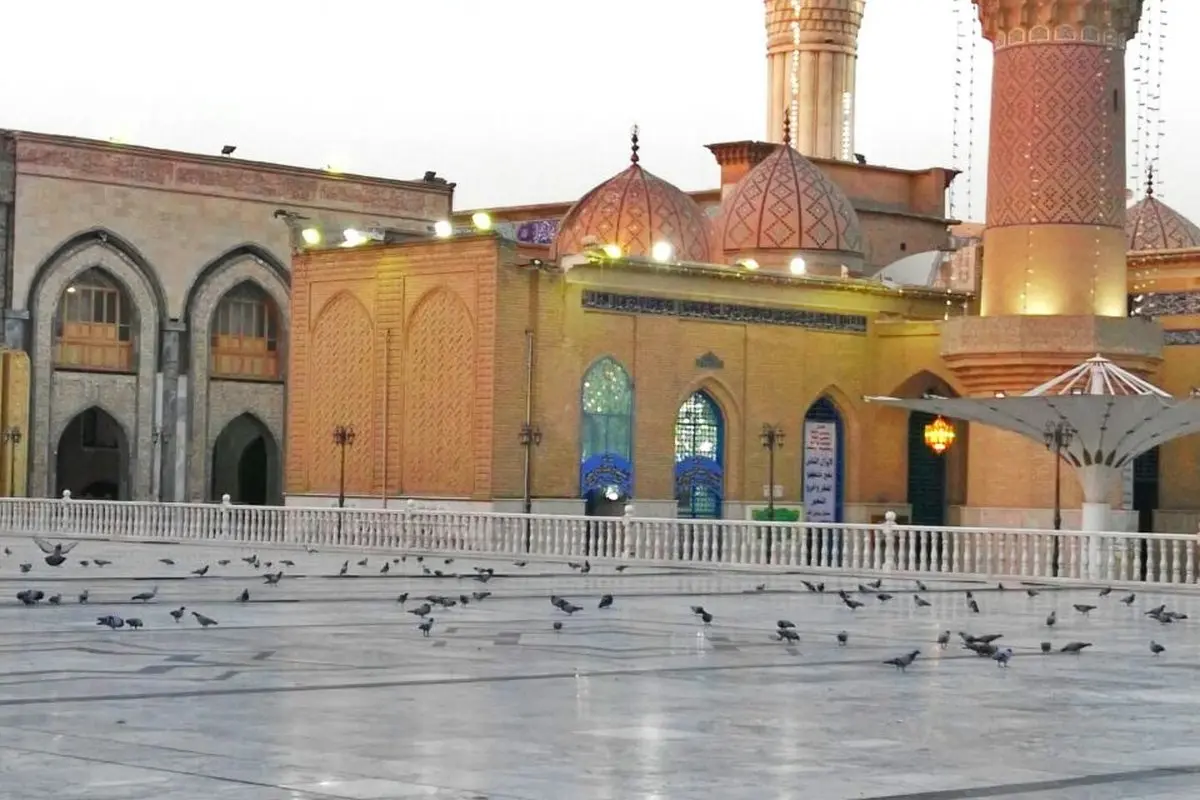 Abdülkadir Geylani Türbesi'nin mermer avlusunda yürüyen güvercinler, arkada çinili kubbeler ve tuğla minareler