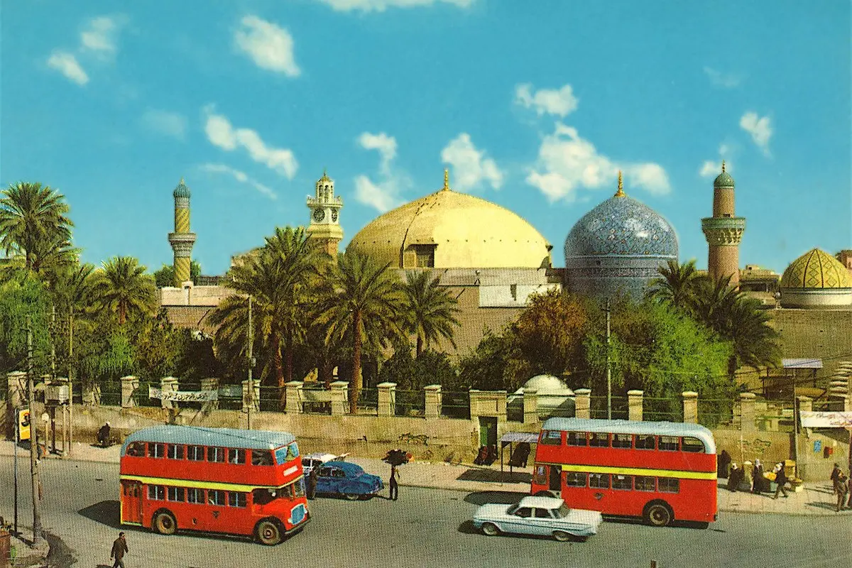 1960'larda Bağdat'ta Abdülkadir Geylani Camii: altın sarısı ve çinili mavi kubbeler, palmiyeler ve önünden geçen kırmızı iki katlı otobüsler