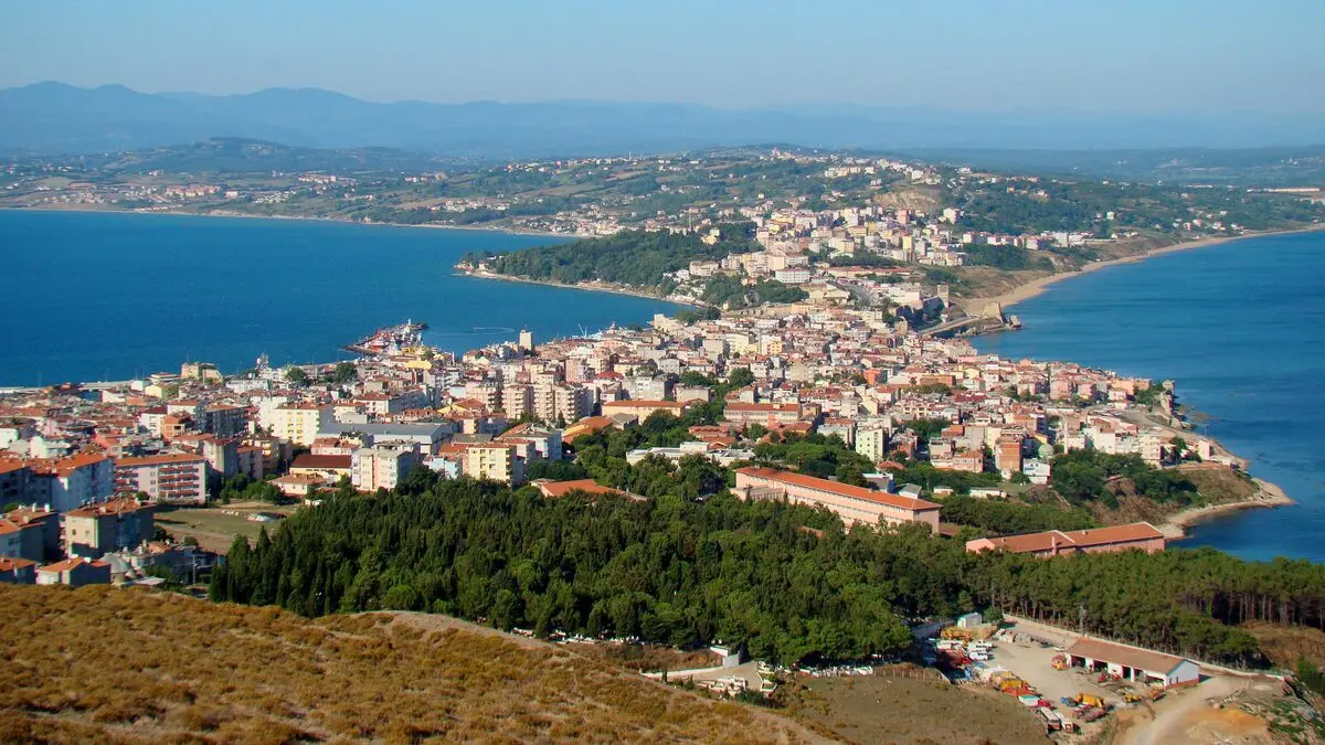 Sabah ışığında iki yanı masmavi denizle çevrili Sinop yarımadası, kırmızı çatılı evler ve ön planda çam ormanı