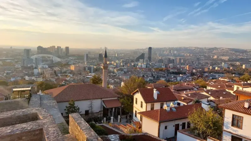 Ankara Kalesi’nden şehrin görünümü: önde kırmızı kiremitli eski Ankara evleri ve Alaeddin Camii’nin minaresi, arkada gün batımında modern binalar