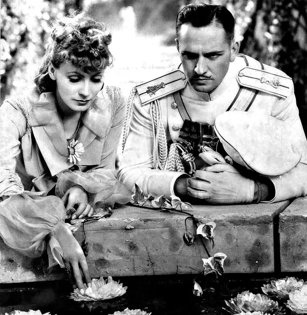 1935 yapımı Anna Karenina filminden siyah beyaz tanıtım fotoğrafı; açık renk elbiseli Greta Garbo ile apoletli beyaz üniformalı Fredric March bir havuzun taş kenarına yaslanmış; Garbo elini sudaki nilüferlere uzatıyor