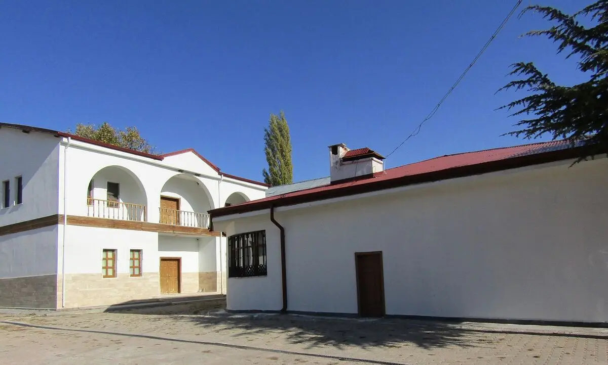 Sivrialan’daki Âşık Veysel Müzesi: beyaz badanalı, kemerli balkonlu iki katlı ev ve yanında kırmızı çatılı uzun ek bina, mavi gökyüzü altında