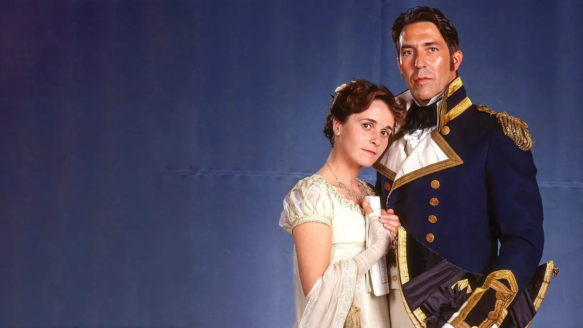 Persuasion (1995) tanıtım görseli: mavi zemin önünde beyaz elbiseli Anne Elliot rolündeki Amanda Root ve deniz subayı üniformalı Kaptan Wentworth rolündeki Ciarán Hinds