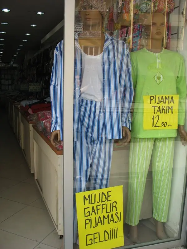 Bir mağaza vitrininde çizgili pijama giydirilmiş manken ve önünde 'Müjde Gaffur pijaması geldi' yazılı sarı karton