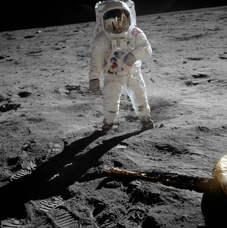 Apollo 11 astronotu Buzz Aldrin beyaz uzay giysisiyle Ay yüzeyinde duruyor; altın renkli vizöründe fotoğrafı çeken Neil Armstrong yansıyor