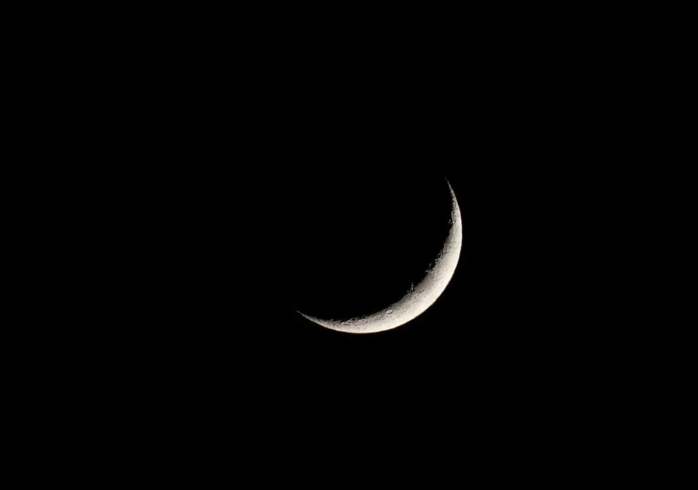 Kapkara gece gökyüzünde ince ve parlak bir hilal