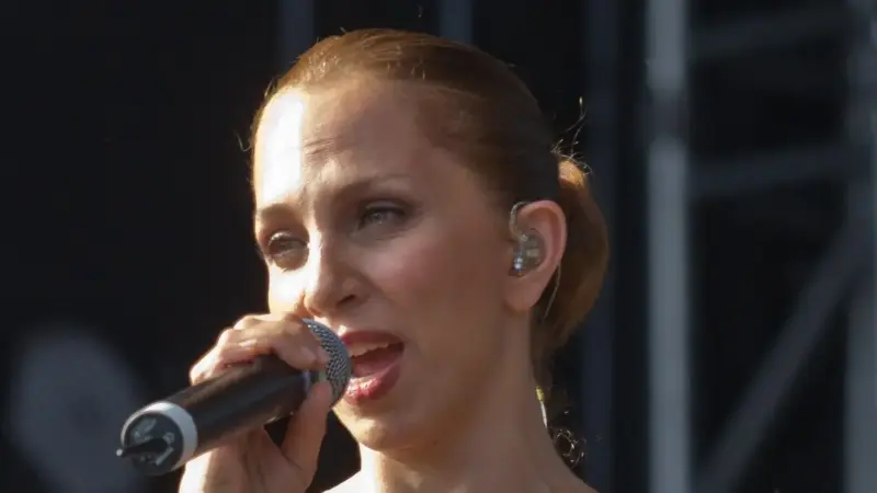 Sertab Erener'in saçlarını arkada toplamış hâlde, kulağında sahne kulaklığıyla mikrofona şarkı söylerken çekilmiş yakın plan konser fotoğrafı