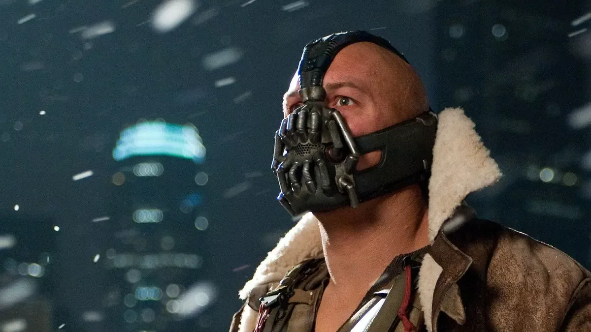 Kara Şövalye Yükseliyor filminden sahne: kar yağan gece şehrinde, yüzünde metal maske ve kürk yakalı ceketiyle Bane rolündeki Tom Hardy