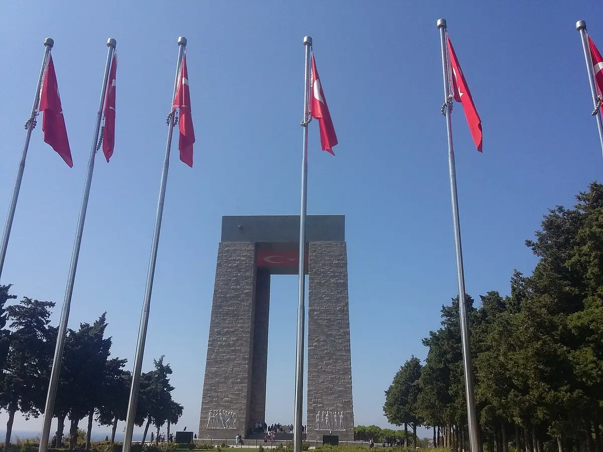 Mavi gökyüzü altında sıra sıra direklerde dalgalanan Türk bayraklarının arasında yükselen dört ayaklı Çanakkale Şehitler Abidesi