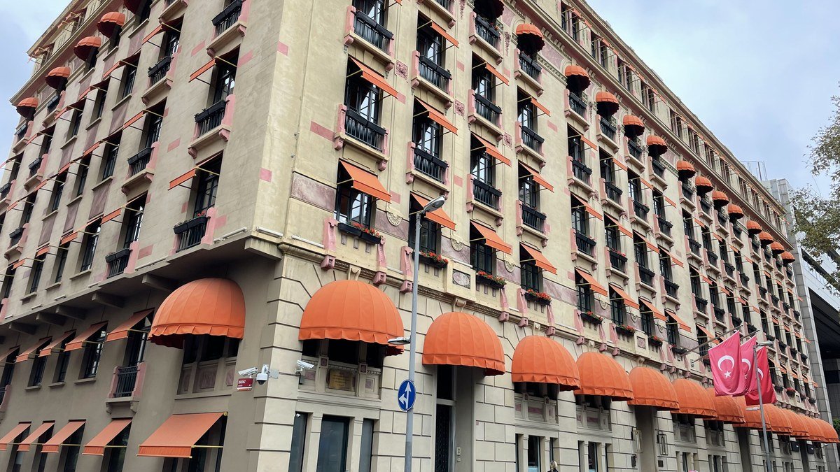 Nişantaşı'nda turuncu tenteli pencereleri ve demir balkonlarıyla köşeyi dönen eski ve büyük bir apartman binası