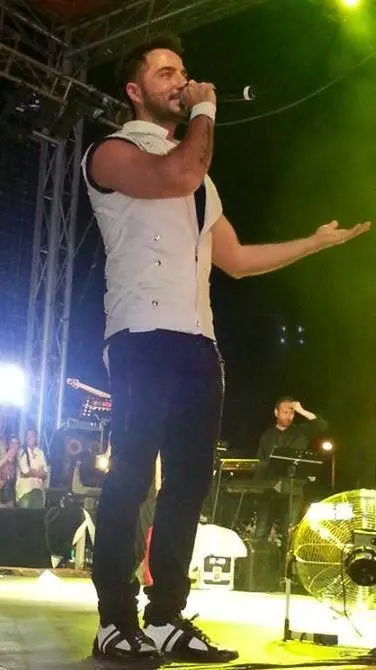 Gökhan Özen’in Kocaeli’deki bir konserde beyaz atlet ve siyah pantolonla sahnede kolunu kaldırıp şarkı söylediği an