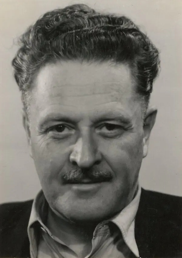 Nâzım Hikmet'in kıvırcık kır saçları, bıyığı, ceketi ve yakası açık gömleğiyle kameraya doğru baktığı siyah-beyaz portre fotoğrafı