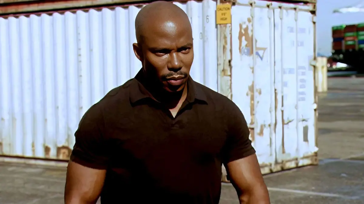 Dexter dizisinden sahne: konteyner sahasında beyaz bir konteynerin önünde kaşlarını çatmış duran Çavuş James Doakes rolündeki Erik King