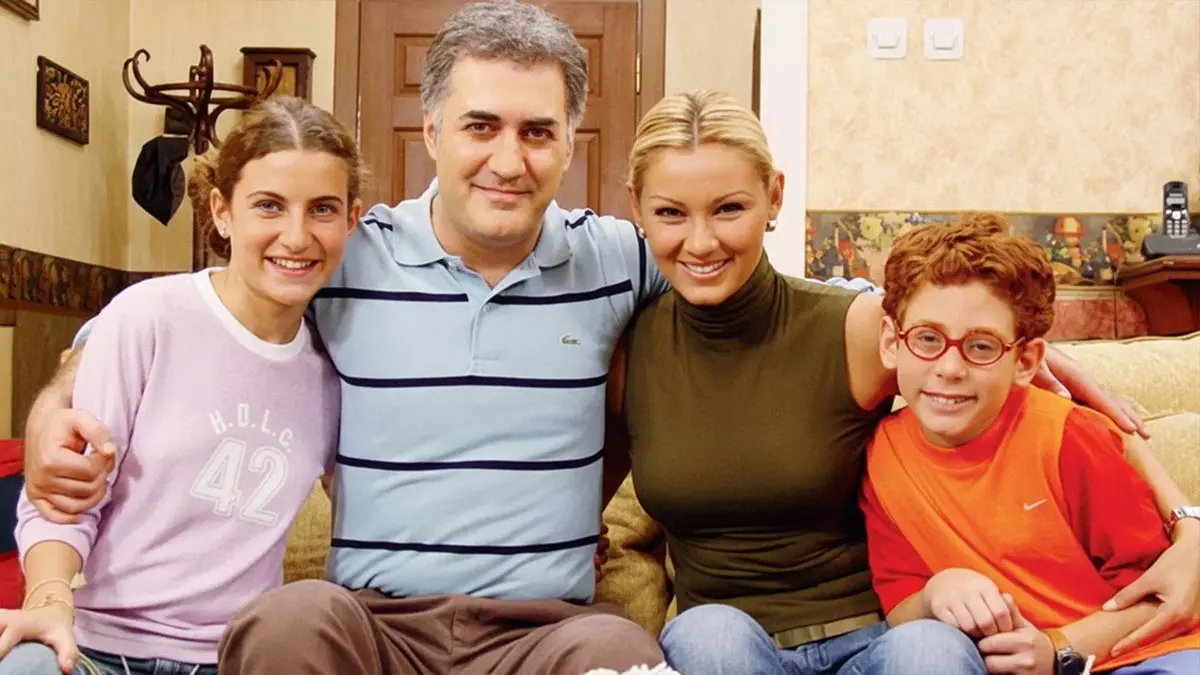 Çocuklar Duymasın dizisinin tanıtım görselinde evin salonunda kanepede birbirine sarılmış oturan anne, baba ve iki çocuk