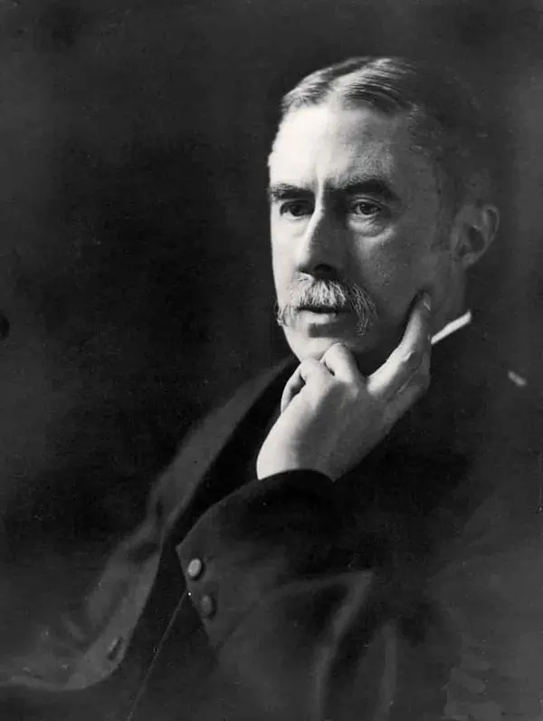 Bıyıklı A. E. Housman’ın takım elbiseyle, elini çenesine dayayıp düşünceli bir ifadeyle baktığı siyah-beyaz fotoğraf