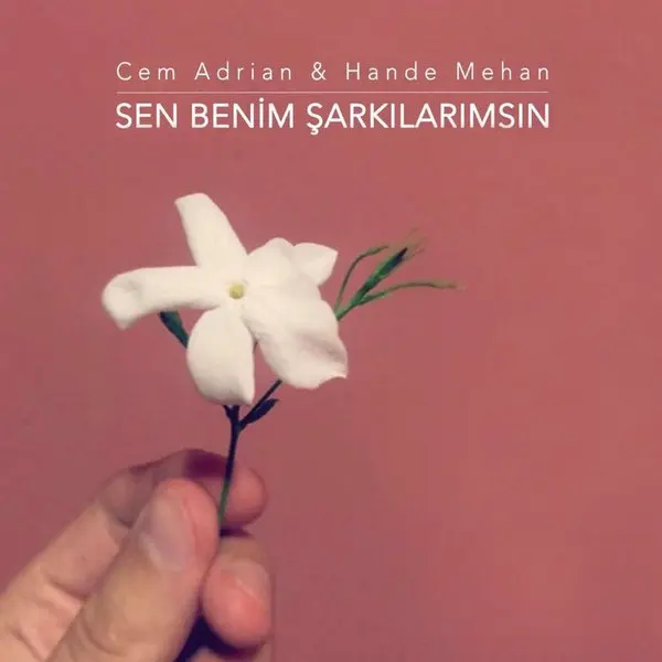 Cem Adrian ve Hande Mehan’ın Sen Benim Şarkılarımsın tekli kapağı; pembe zemin üzerinde bir elin tuttuğu beyaz yasemin çiçeği