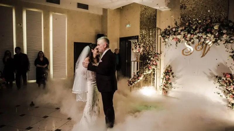 Gelin ve damat, çiçeklerle süslenmiş düğün salonunda yerden yükselen beyaz sis içinde ilk danslarını yapıyor
