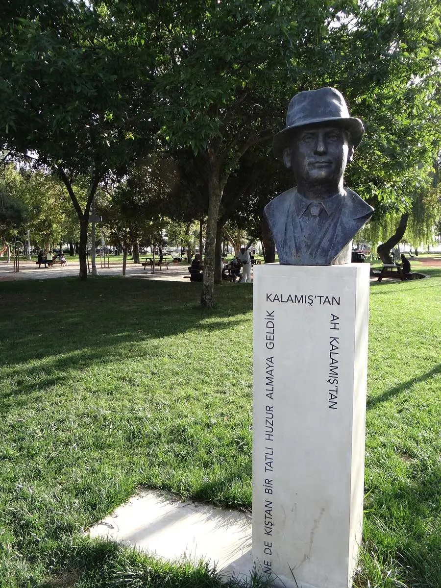 Kadıköy Kalamış Parkı’nda yeşil çimenler arasında beyaz kaide üzerinde duran şapkalı Münir Nurettin Selçuk büstü