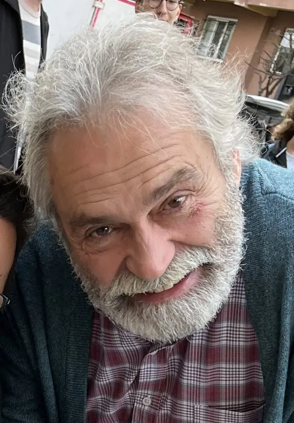Beyaz saçlı ve sakallı Haluk Bilginer'in ekose gömlek ve yeşil hırkayla gülümseyerek çekilmiş portre fotoğrafı
