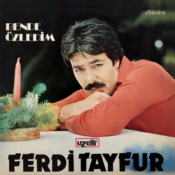 Ferdi Tayfur’un Ben de Özledim albüm kapağı; kırmızı kazaklı Ferdi Tayfur’un mum ve çam dallarının bulunduğu bir masaya kollarını dayamış hâli ve üstte Bende Özledim yazısı