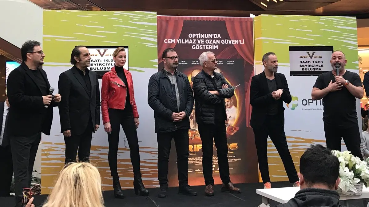 Arif V 216 filminin İzmir galasında sahnede yan yana duran yönetmen ve oyuncular; en sağda mikrofonla konuşan Cem Yılmaz