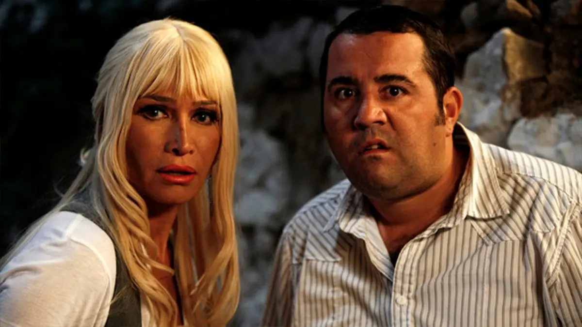 Eyyvah Eyvah filminden, gece kayalık bir yerde şaşkın bakışlarla duran sarı saçlı Demet Akbağ ile çizgili gömlekli Ata Demirer