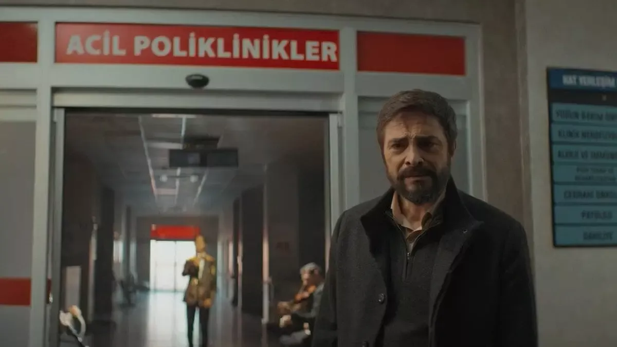 Koyu renk montlu, sakallı Baki'nin (Ahmet Kural) üzerinde kırmızı “ACİL POLİKLİNİKLER” yazan hastane girişinin önünde durduğu sahne; arkadaki koridorda yürüyen insanlar