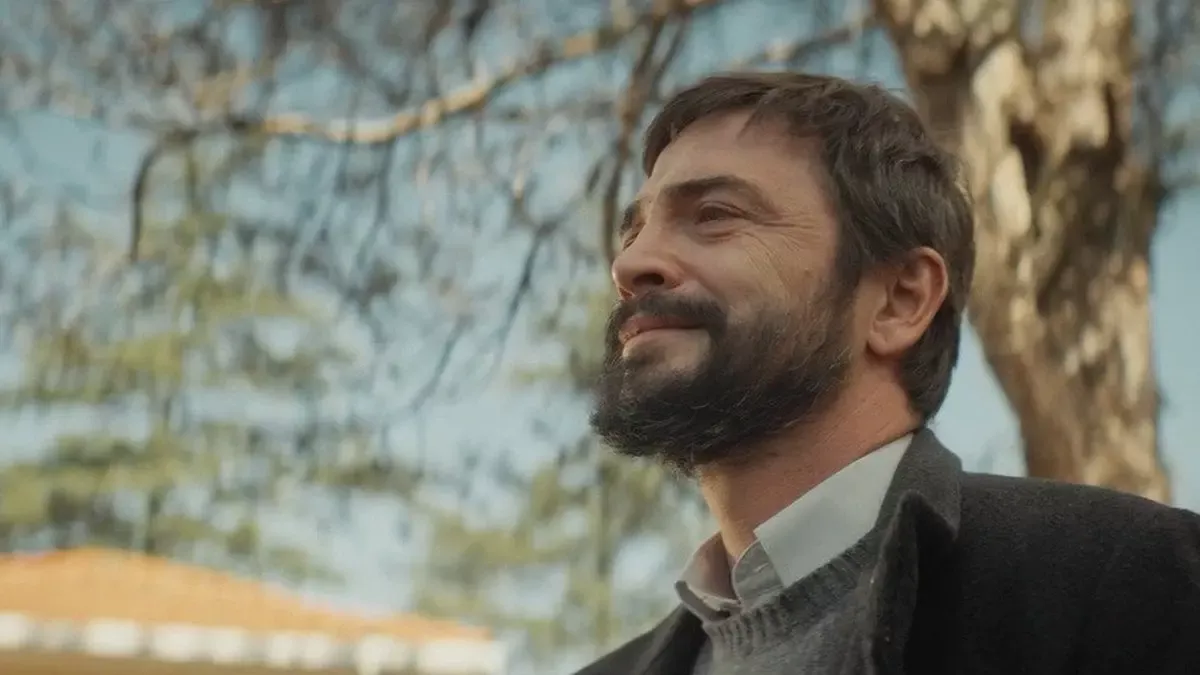 Gri kazaklı, koyu ceketli, sakallı Baki'nin (Ahmet Kural) yapraksız ağaç dallarının altında gökyüzüne doğru bakıp gülümsediği yakın plan