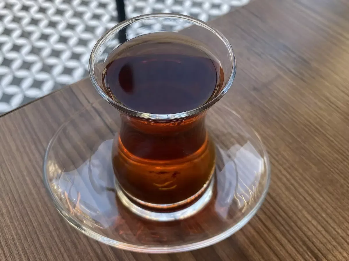 Ahşap masada cam tabak üzerinde ince belli bardakta demli Türk çayı