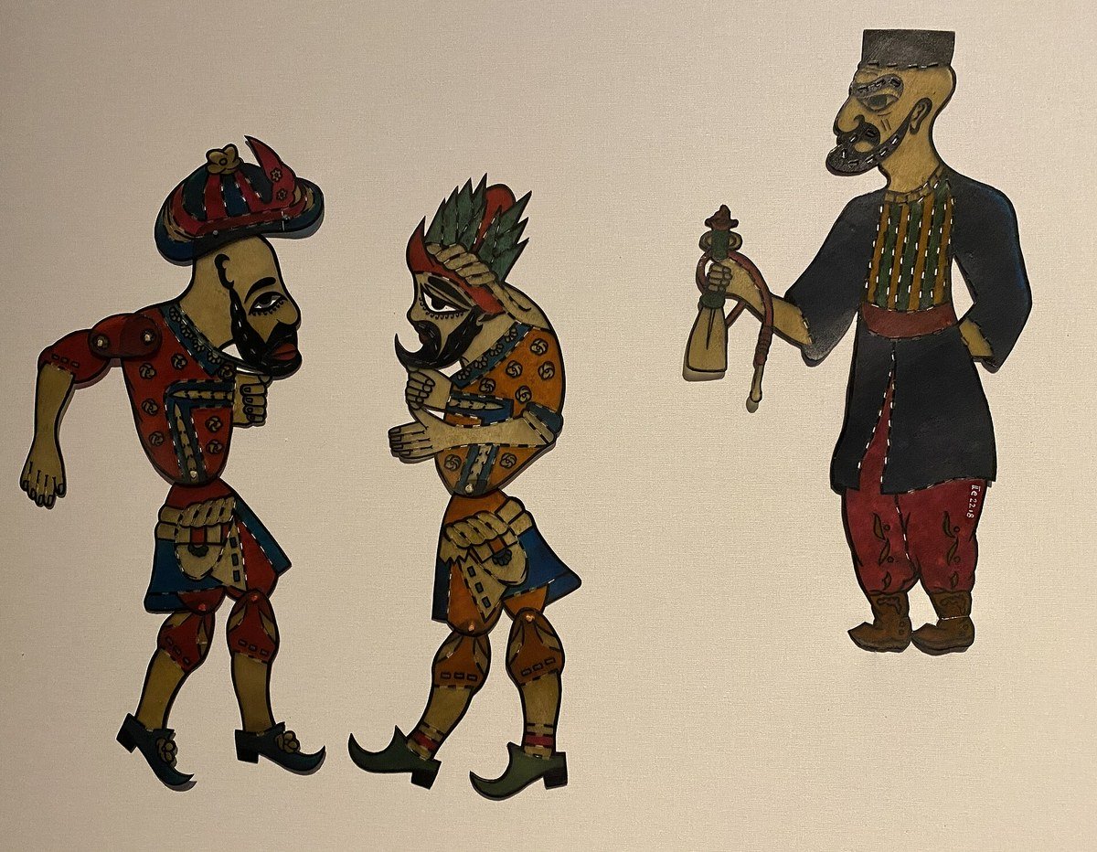 Renkli deri tasvirler hâlinde Karagöz, Hacivat ve elinde nargile taşıyan Tiryaki gölge oyunu figürleri