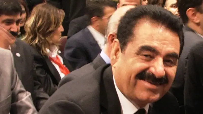 İbrahim Tatlıses’in 2007’de bir salonda koyu takım elbise, beyaz gömlek ve kravatla, kalabalığın önünde gülümseyerek objektife baktığı fotoğraf
