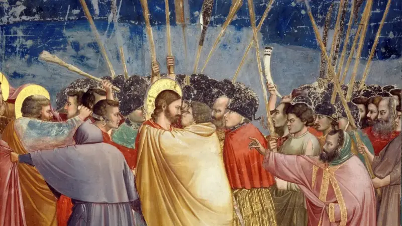 Giotto’nun Yahuda’nın Öpücüğü freski: sarı pelerinli Yahuda İsa’yı kucaklayıp öperken çevrelerinde meşale, sopa ve mızrak kaldırmış kalabalık, sağda eliyle İsa’yı işaret eden başrahip