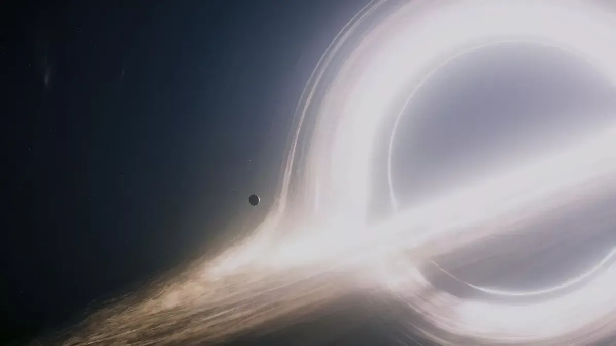 Interstellar filminden sahne: karanlık uzayda ışık halkasıyla parlayan dev kara delik Gargantua ve önündeki küçük bir gezegen