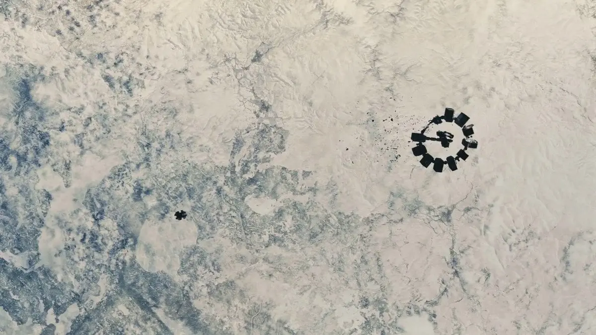 Interstellar filminden sahne: buzlarla kaplı Mann’ın gezegeninin üzerinde, yukarıdan görülen halka biçimli Endurance uzay gemisi