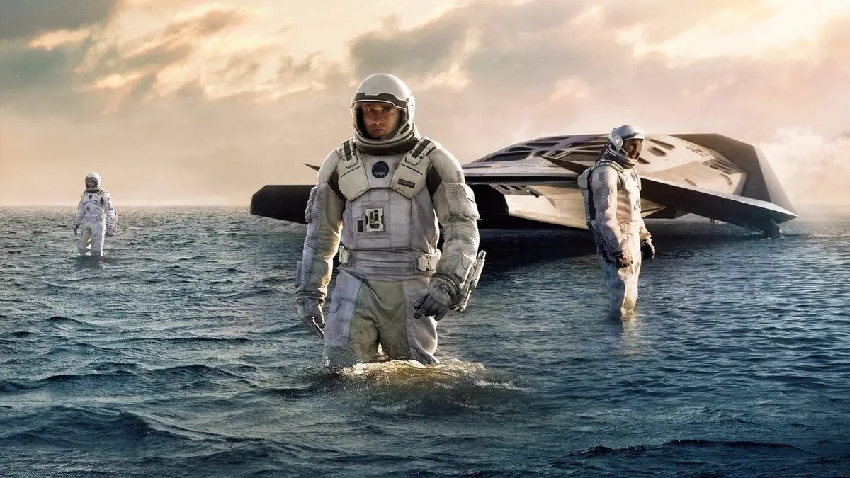 Interstellar filminden sahne: Miller’ın gezegeninde diz boyu suyun içinde yürüyen uzay giysili Cooper, arkada Ranger aracı ve iki astronot