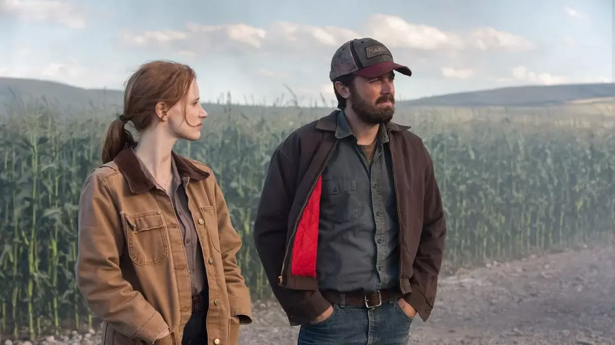 Interstellar filminden sahne: mısır tarlasının kenarında yan yana duran yetişkin Murph ve şapkalı ağabeyi Tom