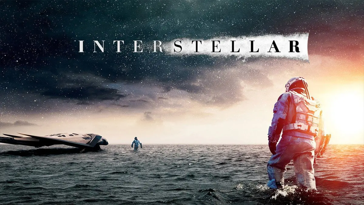 Interstellar tanıtım görseli: gün batımında sığ suyla kaplı Miller’ın gezegeninde yürüyen uzay giysili astronotlar, solda Ranger uzay aracı, üstte INTERSTELLAR yazısı