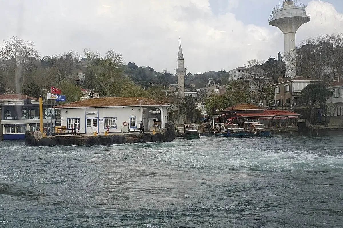 Boğaz kıyısındaki Kanlıca iskelesi, arkasında yeşil tepe, cami minaresi ve beyaz bir kule