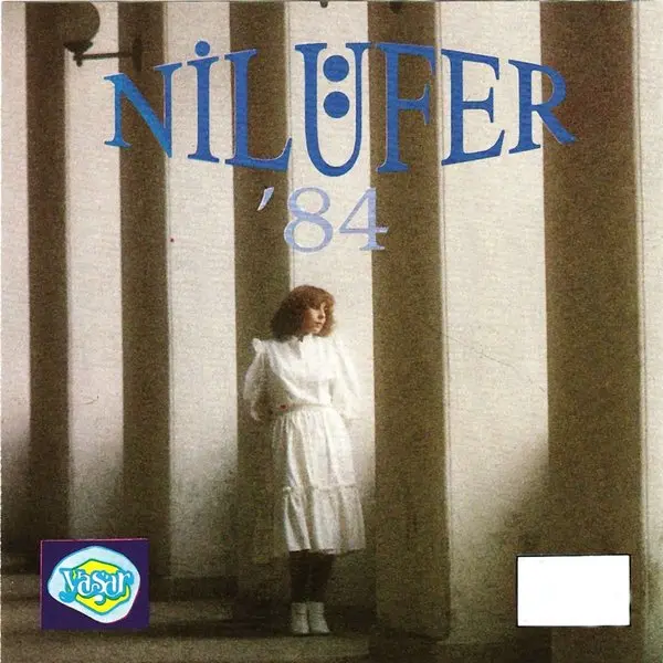 Nilüfer’in Nilüfer ’84 albüm kapağı; kalın sütunların önünde beyaz elbiseli Nilüfer ve üstte mavi harflerle albüm adı