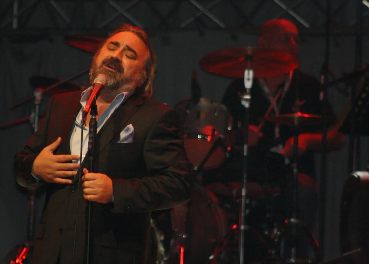 Volkan Konak’ın Ekim 2011’de bir konserde, elini göğsüne koyarak mikrofona şarkı söylerken çekilmiş fotoğrafı; arkada davul çalan müzisyen