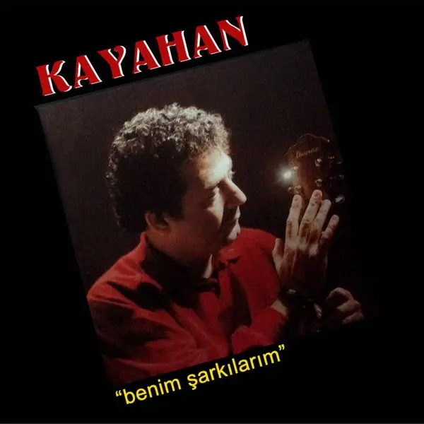 Kayahan’ın Benim Şarkılarım albüm kapağı; siyah fonda kırmızı kazaklı Kayahan’ın elini kaldırdığı fotoğraf ve sarı el yazısıyla albüm adı