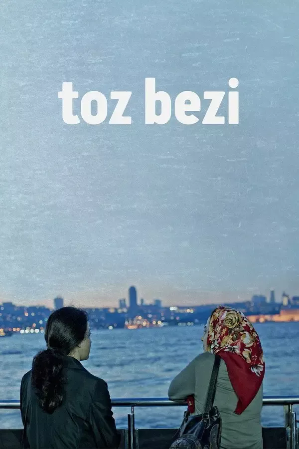Toz Bezi filminin afişi: mavi tonlu bir sahilde denize bakan iki kadın, birinin başında renkli bir başörtüsü var; arkada İstanbul’un siluet hâlindeki kıyısı ve üstte toz bezi yazısı