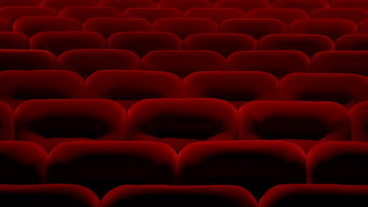 Boş bir sinema salonunda sıra sıra dizilmiş kırmızı kadife koltuklar
