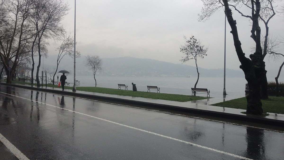 Yağmurlu bir günde Kireçburnu sahili, ıslak yol, çıplak ağaçlar, banklar ve arkada sisli Boğaz